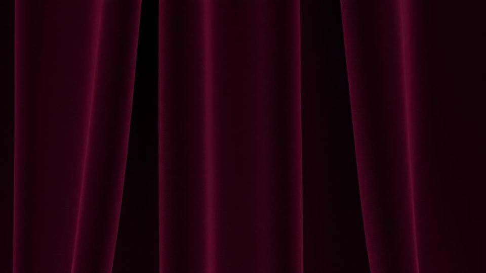 Close-up of folded dark wine velvet catching a soft brass rim light